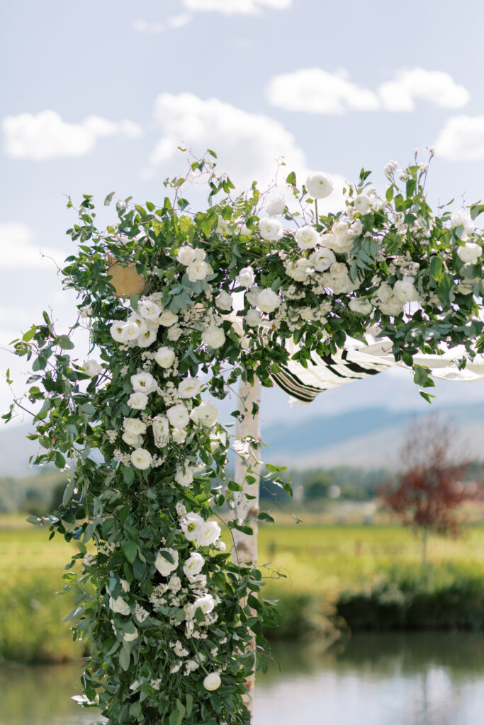 Jewish wedding ceremony at River Bottoms Ranch featuring a lush greenery chuppah with white florals and mountain views in Midway Utah