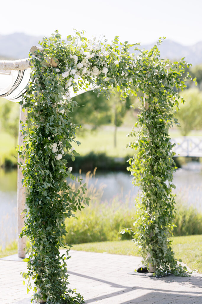 Jewish wedding ceremony at River Bottoms Ranch featuring a lush greenery chuppah with white florals and mountain views in Midway Utah