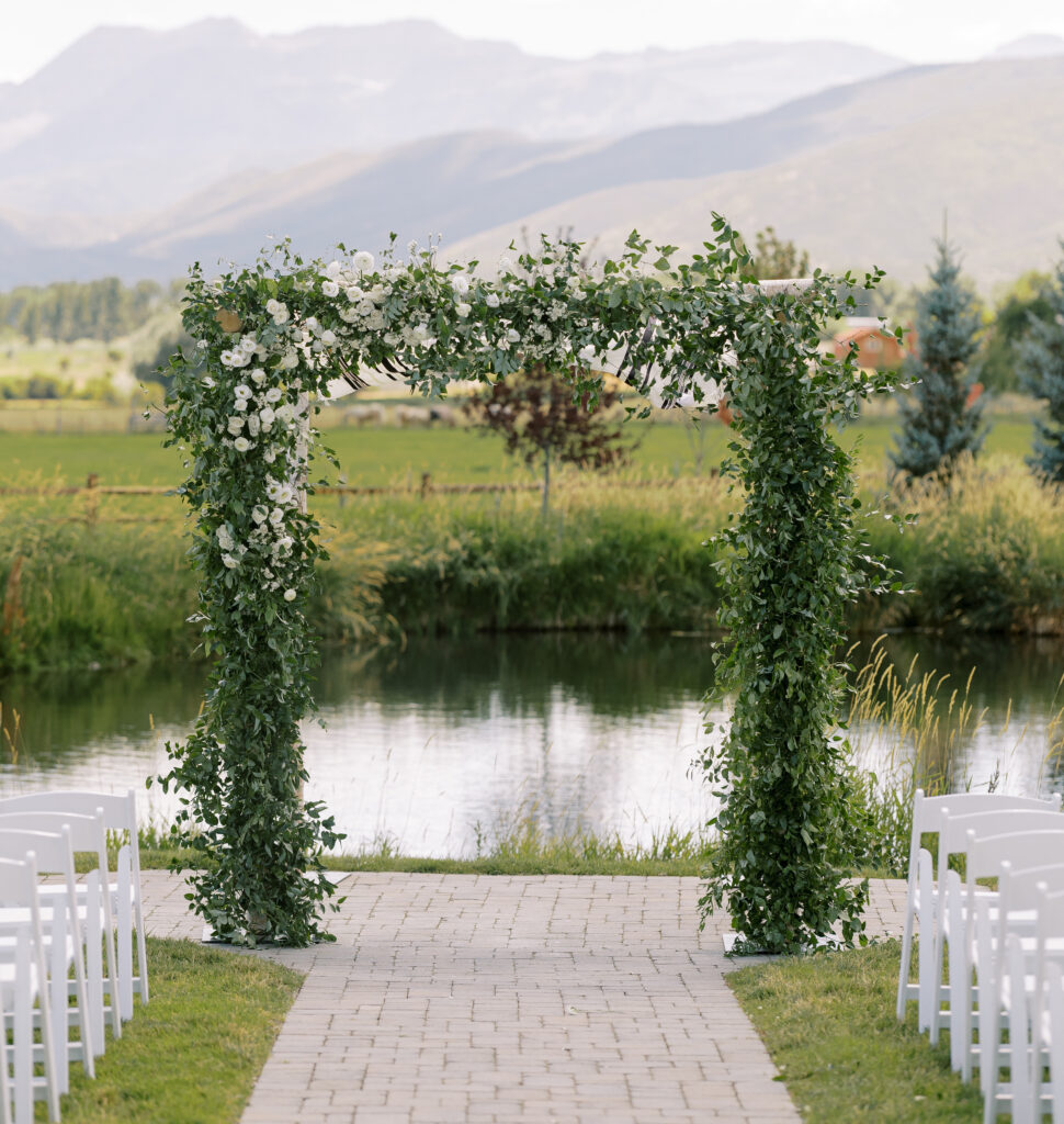 Jewish wedding ceremony at River Bottoms Ranch featuring a lush greenery chuppah with white florals and mountain views in Midway Utah