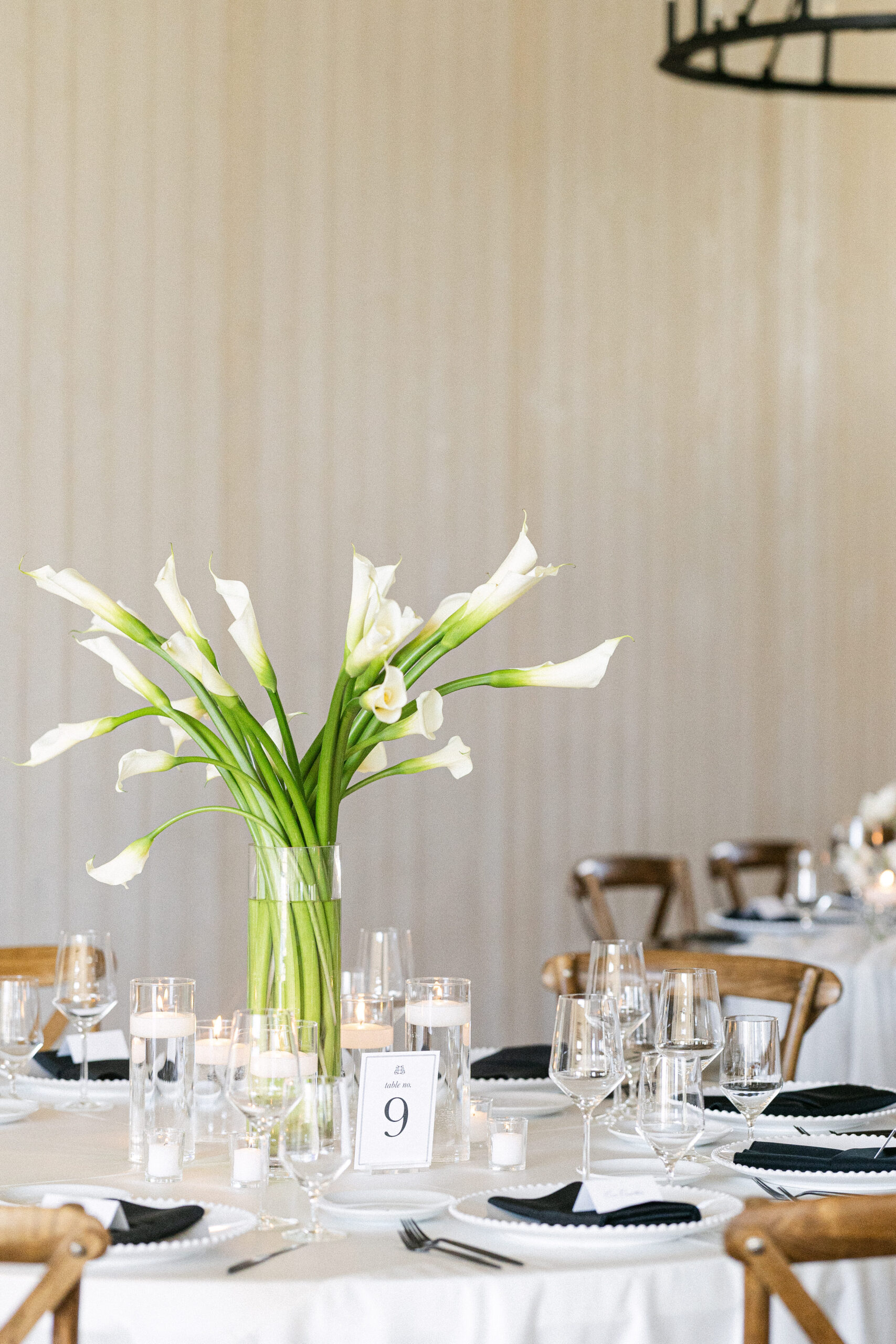 Round wedding reception tables with tall white calla lily centerpieces and candlelight at River Bottoms Ranch