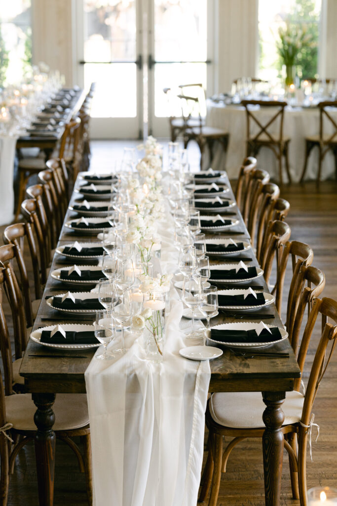 White wedding florals on farmhouse tables with modern bud vases, floating candles, and black accents at River Bottoms Ranch wedding in Midway Utah
