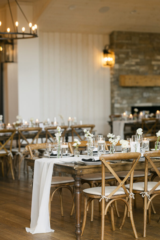 Elegant wedding reception at River Bottoms Ranch with white florals, wood chairs, candlelight, and garden-inspired tablescapes by a Utah wedding florist